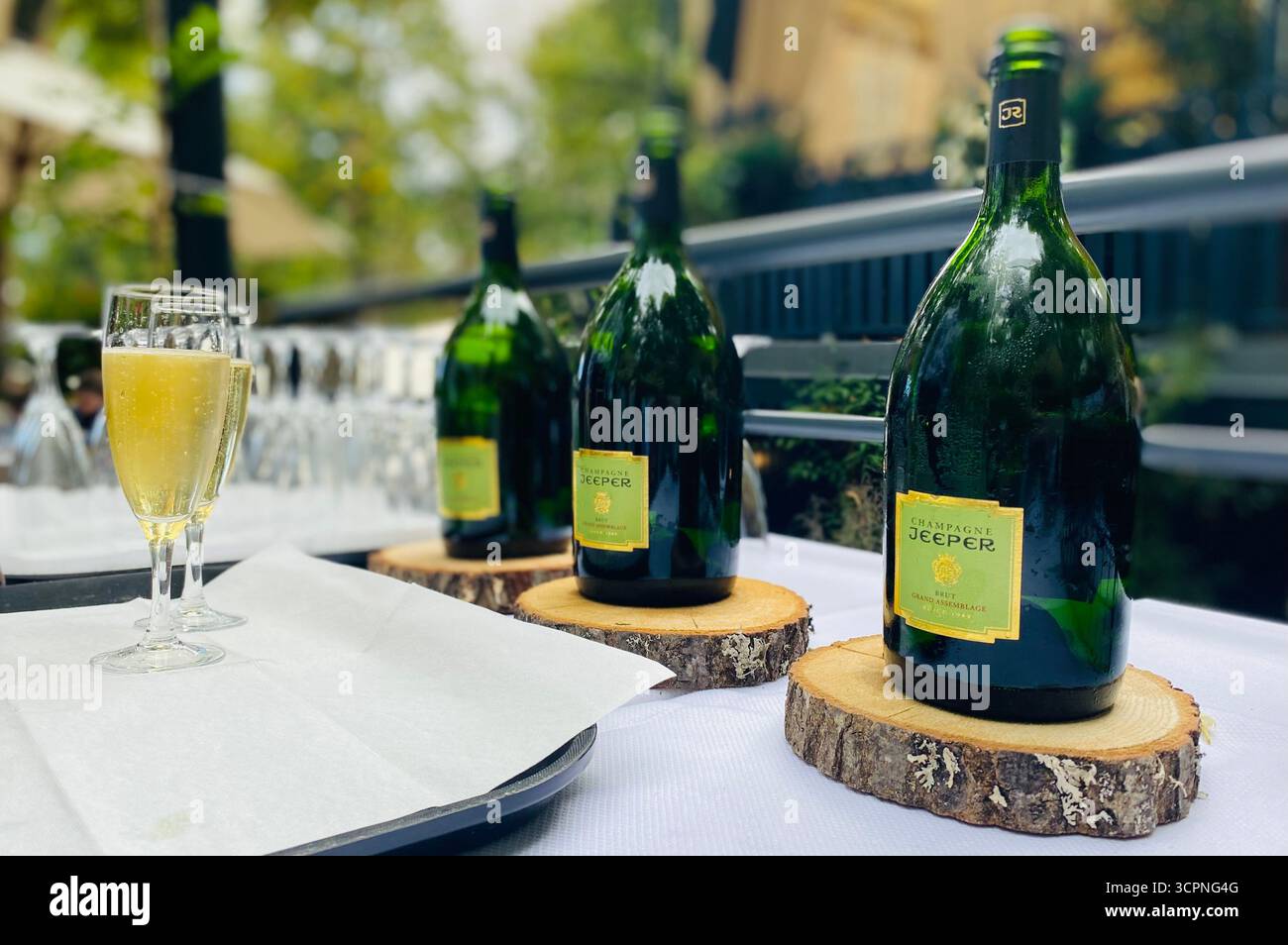Bouteilles de champagne Jeeper avec verre pétillant sur table élégante en extérieur - Image de stock capturée avec un smartphone