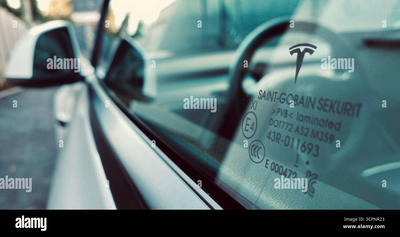 Vitre côté conducteur Tesla avec marquages réfléchissants sur le tableau de bord et d'homologation - Image de stock capturée avec un smartphone