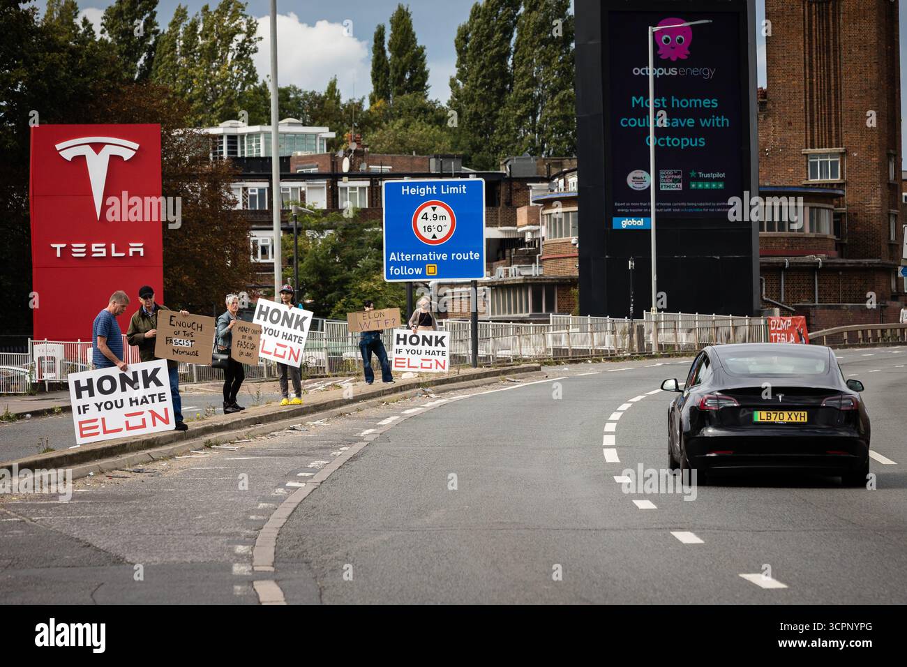 LONDRES, Royaume-Uni - 27 septembre 2025 : des activistes du groupe de campagne Tesla Takedown manifestent devant le showroom Tesla dans l'ouest de Londres, près de la gare Park Royal. Les manifestants portaient des pancartes et des banderoles contre Elon Musk, condamnant son récent discours vidéo à la marche d’extrême droite Unite the Kingdom à Londres, ses liens avec Donald Trump, et un nouvel accord du gouvernement américain pour déployer son chatbot Grok. Les militants ont accusé Musk d'alimenter les mouvements d'extrême droite et anti-immigrés. Banque D'Images