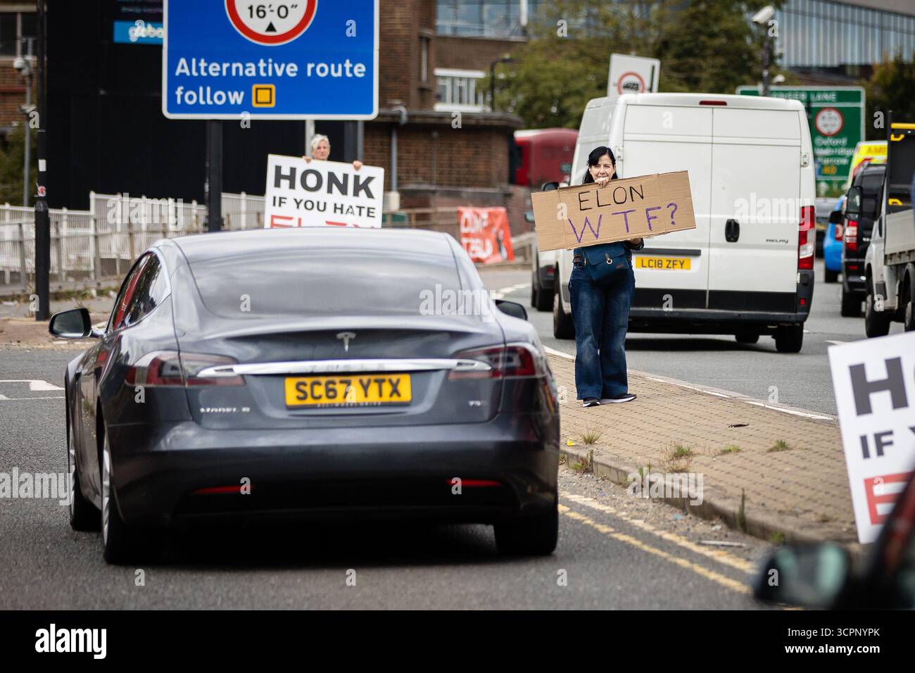 LONDRES, Royaume-Uni - 27 septembre 2025 : des activistes du groupe de campagne Tesla Takedown manifestent devant le showroom Tesla dans l'ouest de Londres, près de la gare Park Royal. Les manifestants portaient des pancartes et des banderoles contre Elon Musk, condamnant son récent discours vidéo à la marche d’extrême droite Unite the Kingdom à Londres, ses liens avec Donald Trump, et un nouvel accord du gouvernement américain pour déployer son chatbot Grok. Les militants ont accusé Musk d'alimenter les mouvements d'extrême droite et anti-immigrés. Banque D'Images