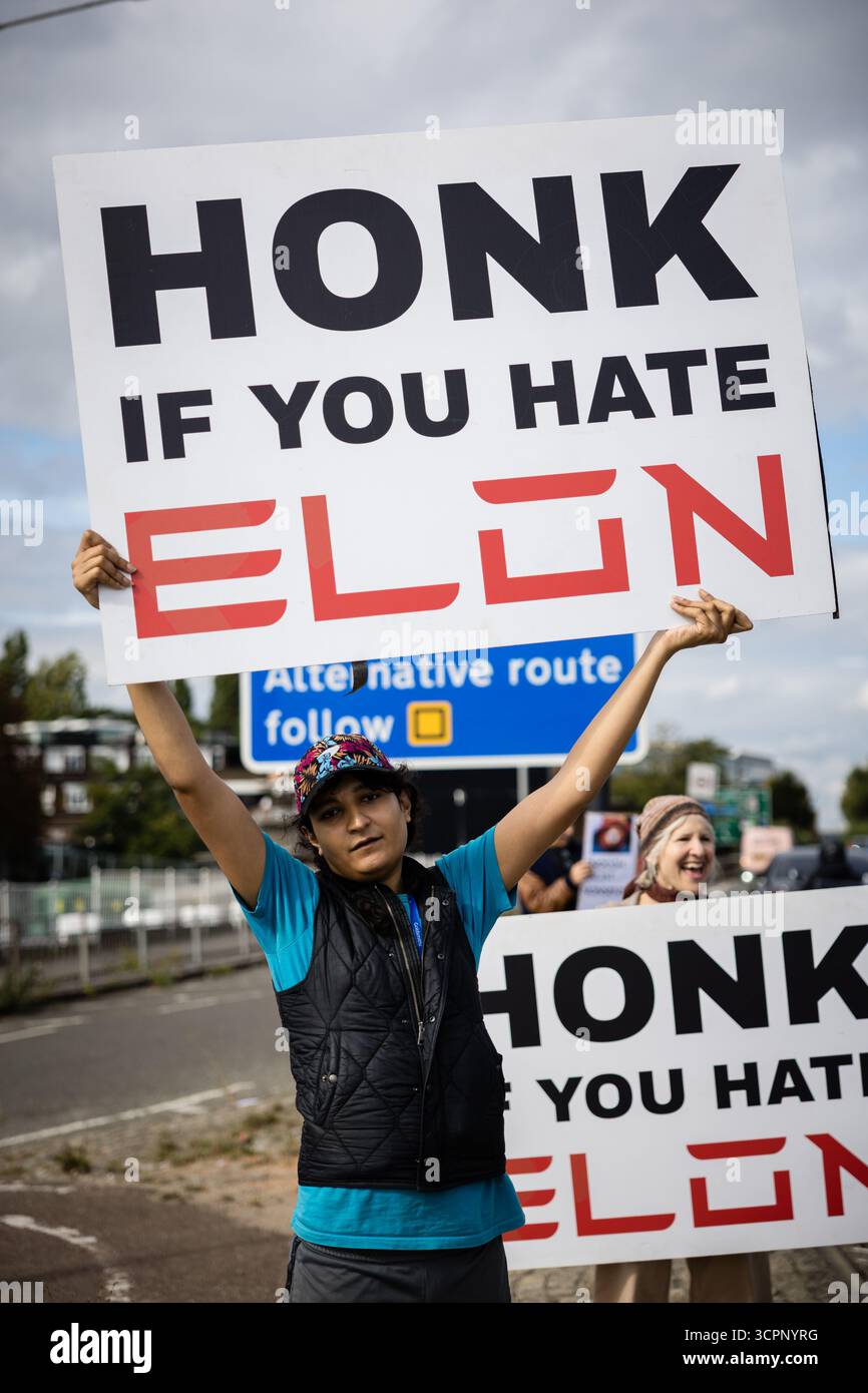 LONDRES, Royaume-Uni - 27 septembre 2025 : des activistes du groupe de campagne Tesla Takedown manifestent devant le showroom Tesla dans l'ouest de Londres, près de la gare Park Royal. Les manifestants portaient des pancartes et des banderoles contre Elon Musk, condamnant son récent discours vidéo à la marche d’extrême droite Unite the Kingdom à Londres, ses liens avec Donald Trump, et un nouvel accord du gouvernement américain pour déployer son chatbot Grok. Les militants ont accusé Musk d'alimenter les mouvements d'extrême droite et anti-immigrés. Banque D'Images