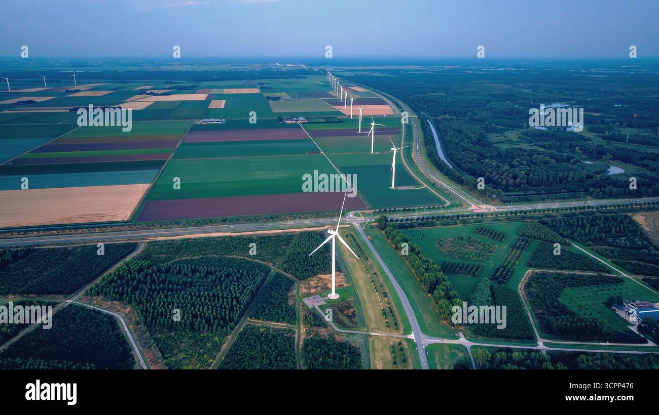 Moulins à vent le long des champs agricoles, après le coucher du soleil. Vue drone du paysage rural du soir avec parc éolien aux pays-Bas. Énergie alternative, Green ener Banque D'Images