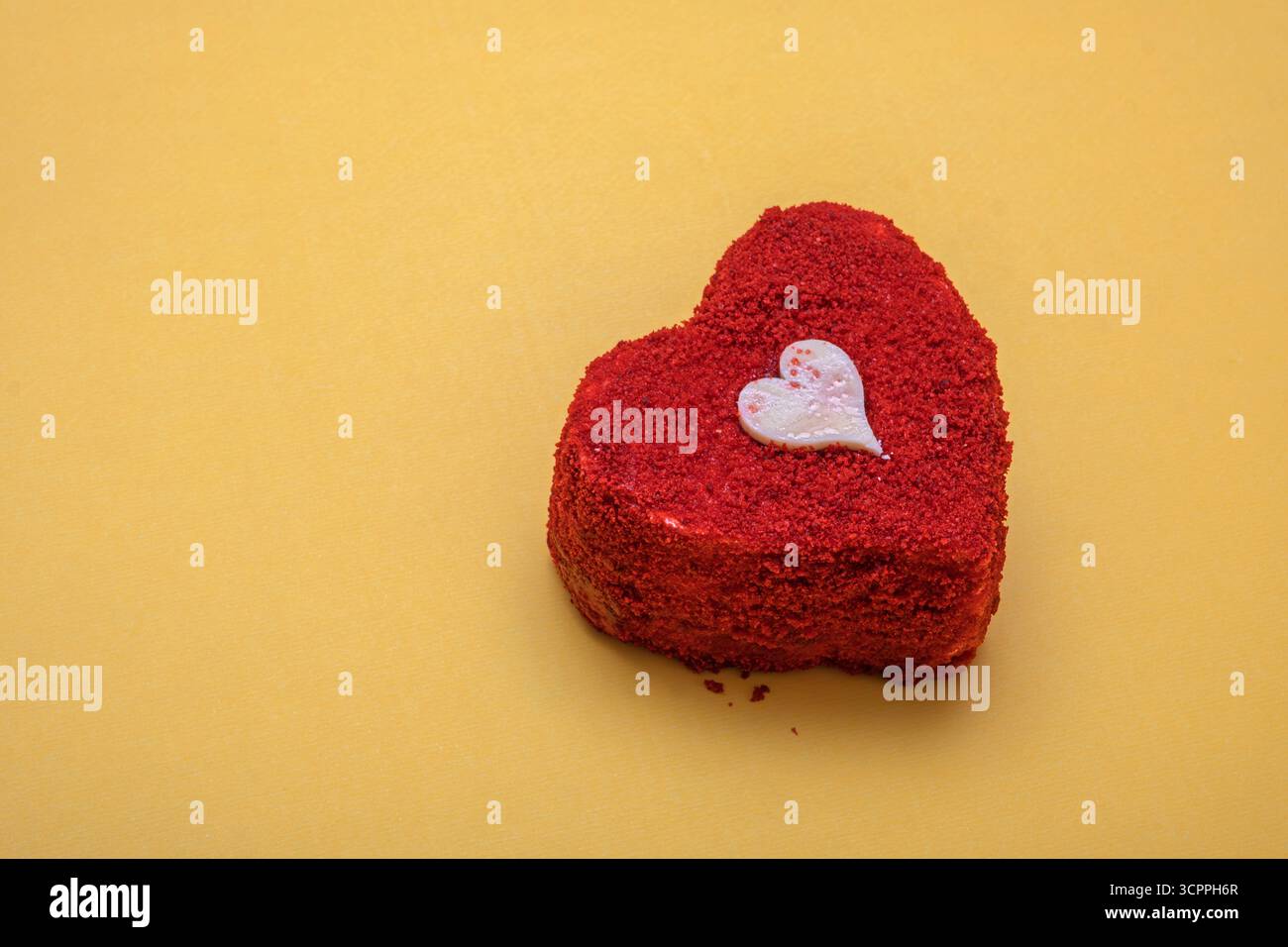 Gâteau de velours rouge en forme de cœur sur fond jaune. Saint-Valentin, anniversaires ou célébrations spéciales. Banque D'Images