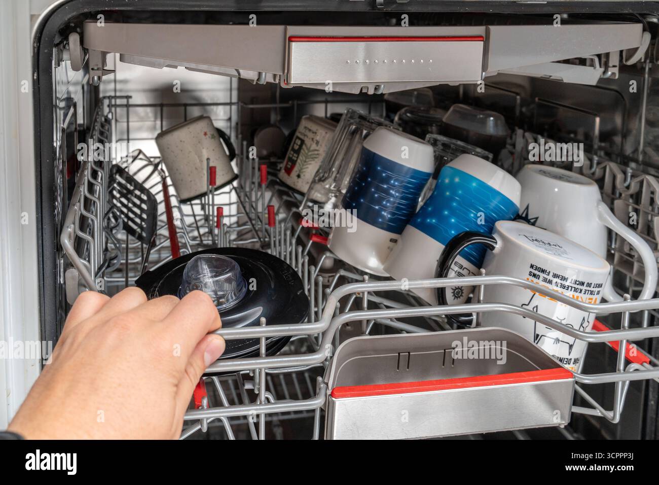 Allemagne - 27 septembre 2025 : une main ferme le lave-vaisselle chargé. Les tasses, les tasses et la vaisselle sont soigneusement disposées et prêtes pour le cycle de lavage, ce qui assure l'hygiène et la propreté dans le ménage. *** Eine hand schiebt den beladenen Geschirrspüler zu. Tassen, Becher und Geschirr sind ordentlich einsortiert und bereit für den Spülvorgang, der Hygiene und Sauberkeit im Haushalt sicherstellt. Banque D'Images