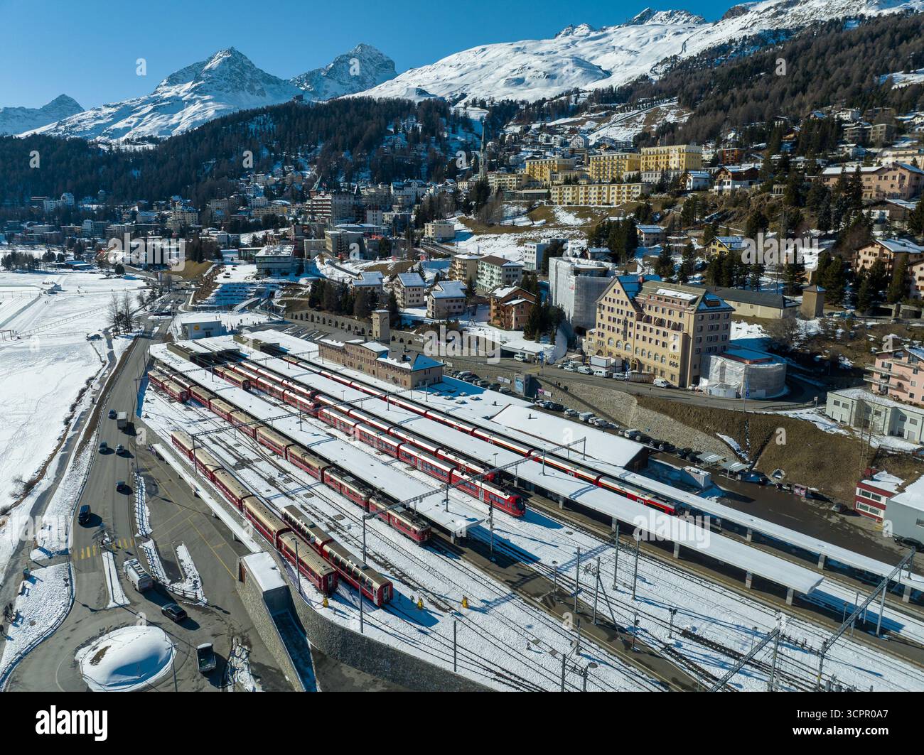 Vue aérienne des trains rouges alignés à la gare de Filisur sur fond de montagnes enneigées et de charmants bâtiments, St moritz, SW Banque D'Images