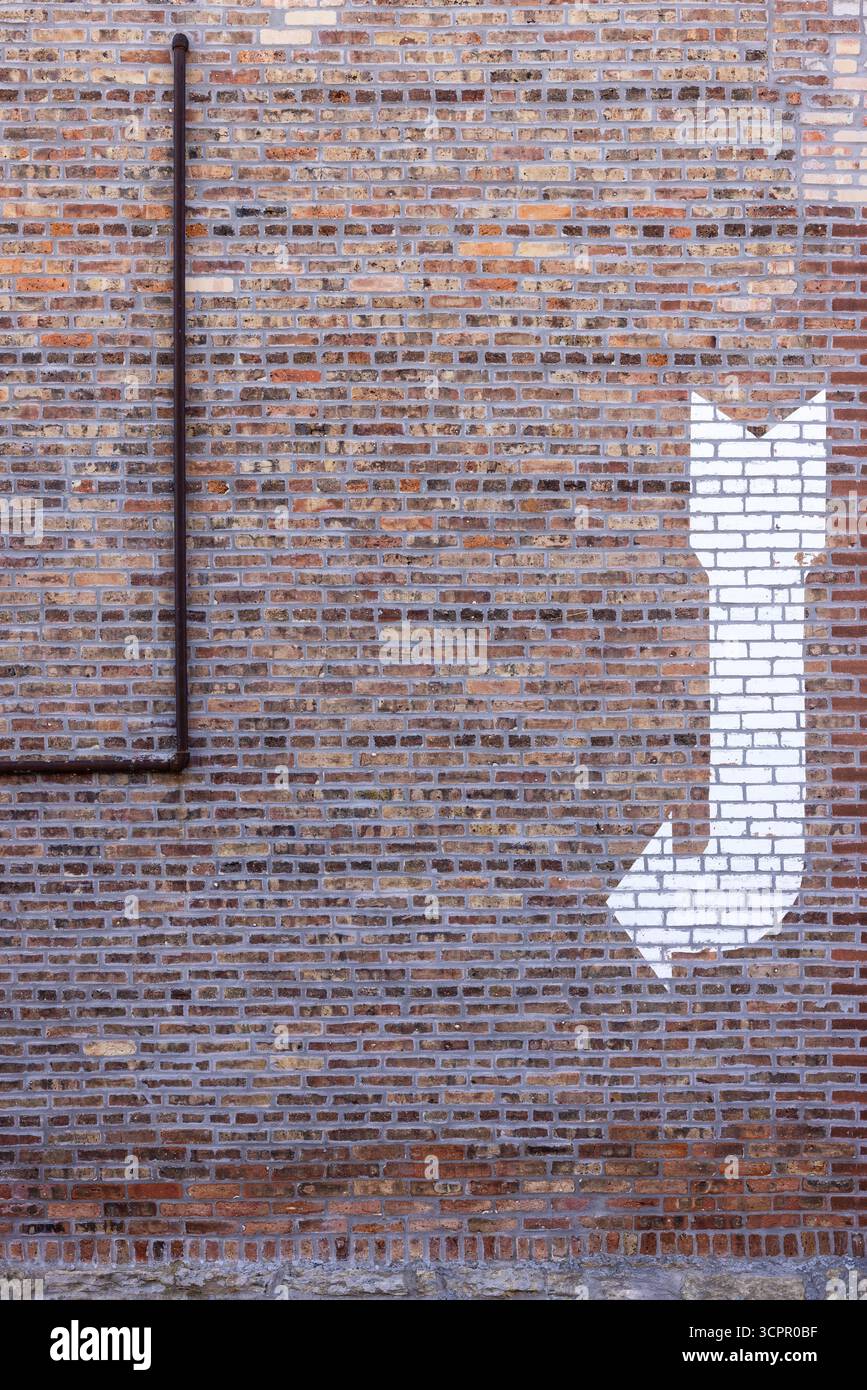 Un mur de briques avec un tuyau et une flèche blanche. Banque D'Images