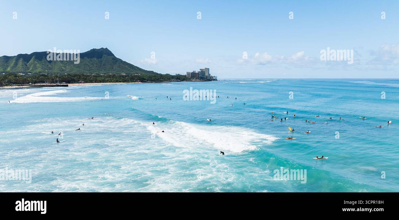 Vue aérienne des vagues turquoises s'écrasant le long du rivage, surfeurs parsemant l'océan sur fond de Diamond Head, Waikiki, Honolulu, Hawaï, États-Unis. Banque D'Images