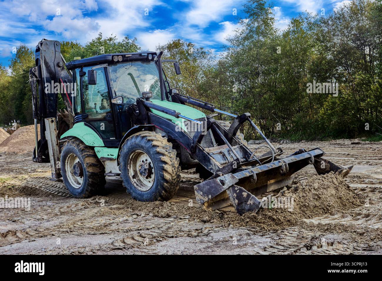Le chargeur frontal effectue des travaux sur site avec des tas de sable présents sur la zone de travail. Banque D'Images