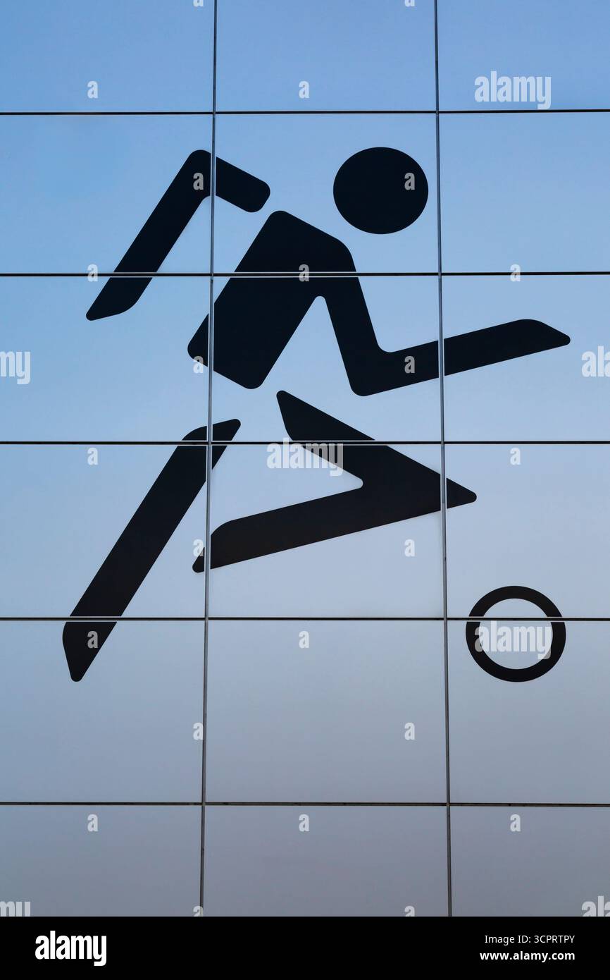 Contour de style numérique noir du joueur de football sur le mur extérieur du bâtiment revêtu de panneaux carrés en métal argenté. Banque D'Images