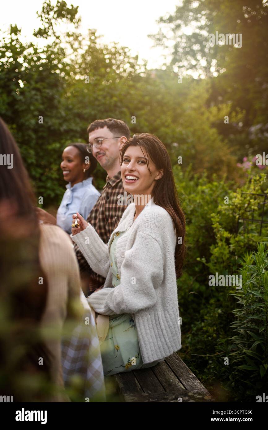 Portrait de jeune femme souriante mangeant un dîner avec des amis lors d'une réunion sociale Banque D'Images