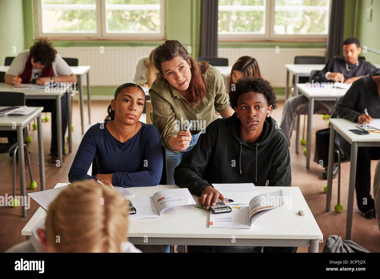 Vue en angle élevé d'une professeure expliquant le problème de mathématiques aux élèves assis à un bureau dans la salle de classe à l'école Banque D'Images
