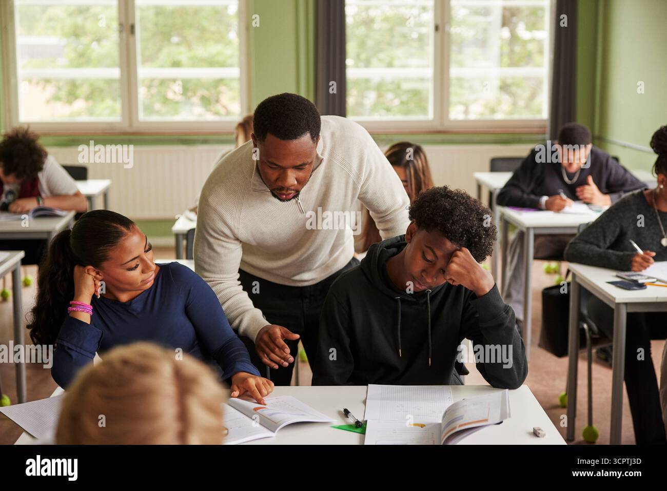 Enseignant masculin aidant les élèves dans les études dans les classes secondaires du premier cycle Banque D'Images