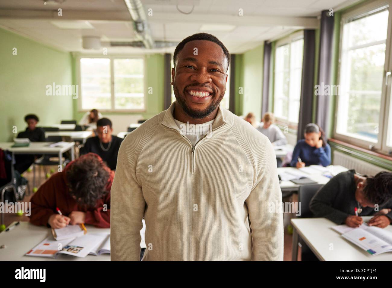 Portrait d'un enseignant masculin heureux debout dans la salle de classe du collège Banque D'Images