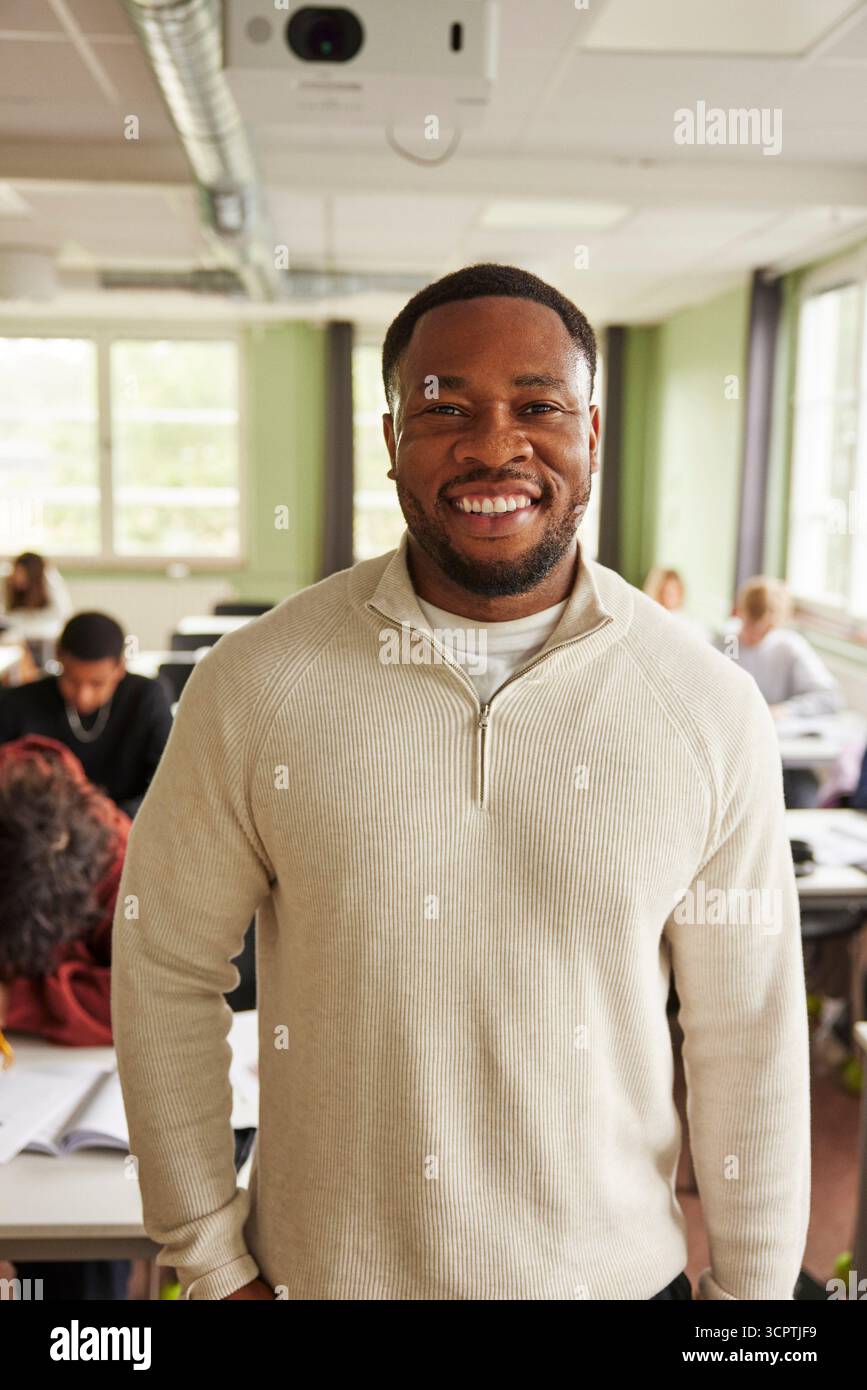 Portrait d'un enseignant masculin souriant confiant debout dans la salle de classe du collège Banque D'Images