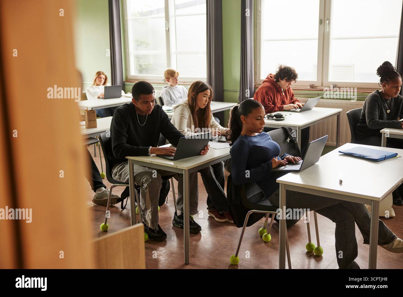 Les adolescents hommes et femmes du premier cycle du secondaire étudient sur ordinateur portable dans la salle de classe à l'école Banque D'Images