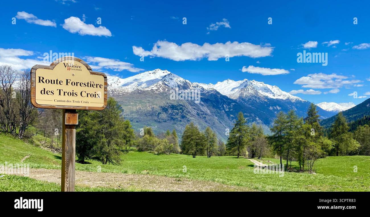 Sentier de montagne dans la Vallée de la Sionne avec panneau en bois et sommets enneigés sous ciel bleu - Image de stock capturée avec un smartphone
