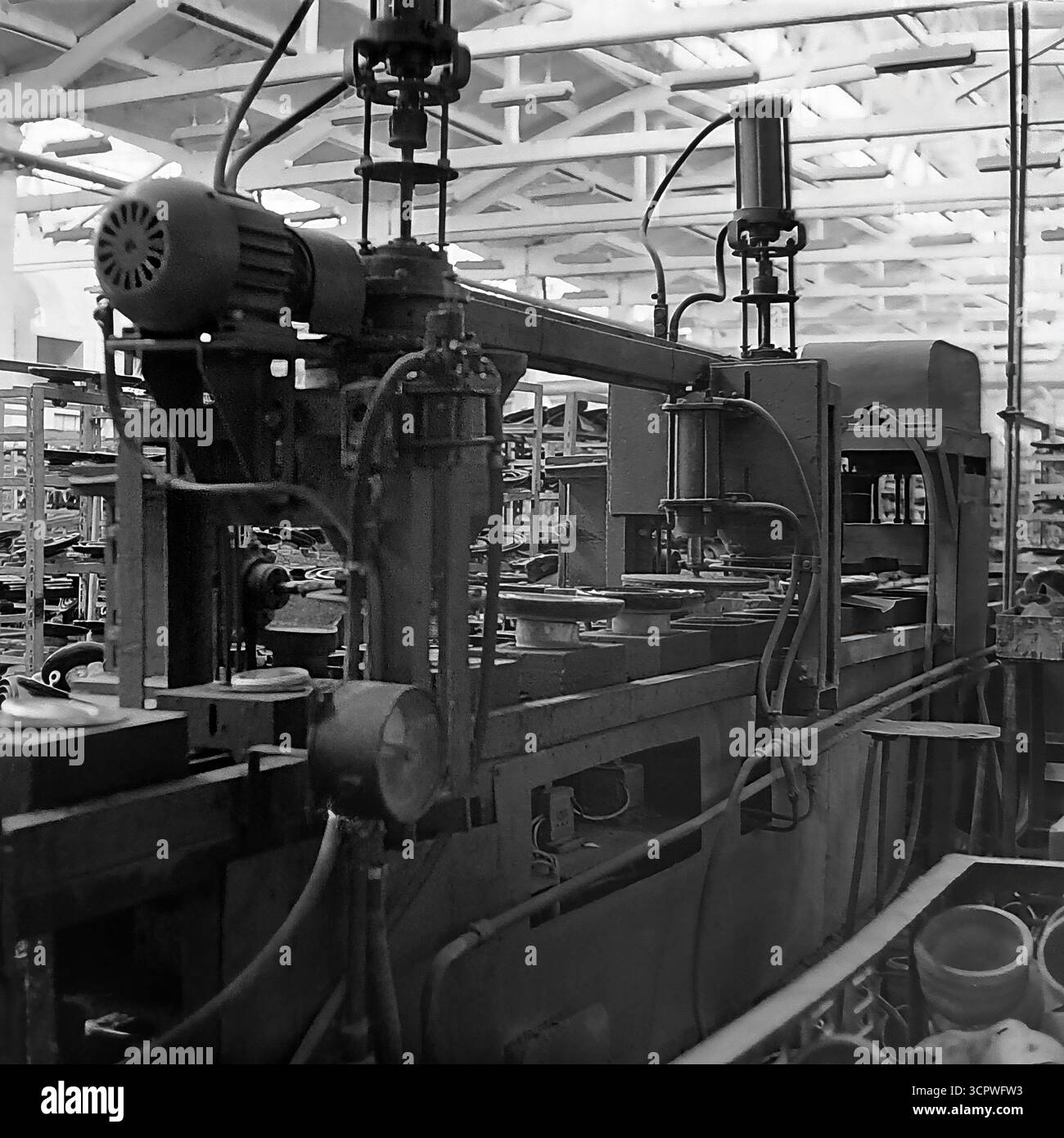 Un gros plan montre une presse industrielle complexe à l'intérieur d'un atelier de l'usine de raccords et d'isolants de Slavyansk (AIZ) dans la RSS d'Ukraine dans les années 1970 Cette photo d'archive monochrome met en évidence les machines lourdes qui alimentaient la fabrication de l'ère soviétique, avec un grand moteur électrique, des pistons hydrauliques et des tringleries mécaniques. Cet équipement était au cœur du processus de production de composants électriques, mettant en valeur la technologie industrielle de la région du Donbass Banque D'Images