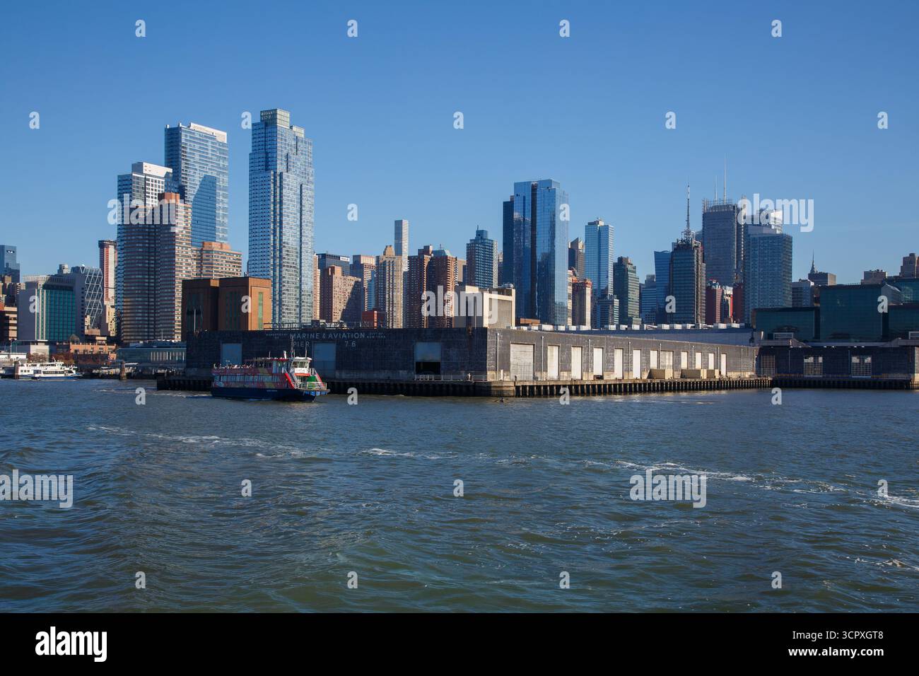 Un Tourboat sur la rive de l'Hudson River, la jetée de l'aviation marine 76 et la ligne d'horizon avec des gratte-ciel sur le côté ouest de Manhattan, New York City, États-Unis Banque D'Images
