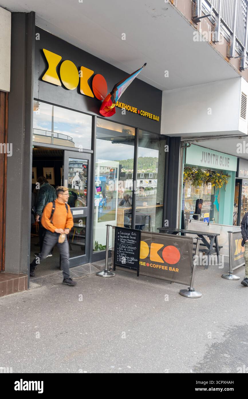 Le client quitte le XOKO Bakehouse Coffee Bar avec drapeau de fierté affiché, Bridge Street, Inverness, Écosse, Royaume-Uni. Banque D'Images