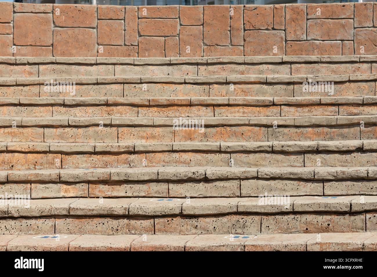 Gros plan d'escaliers extérieurs en pierre avec un mur à motifs en briques. Les escaliers sont vieillis, avec une usure et une décoloration visibles à chaque marche. Banque D'Images