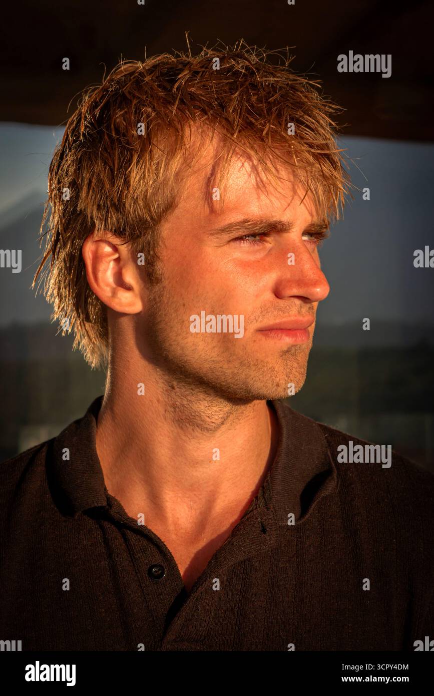 Un bel homme d'environ 23 ans regarde le soleil se coucher en vacances Banque D'Images