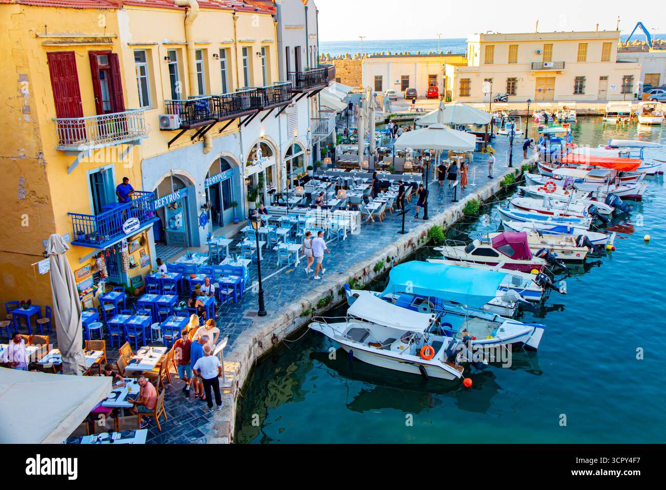 Jolis buidings rustiques jaunes et bleus et restaurants au bord de l'eau dans le vieux port dans la ville industrielle de Rethymnon, Crète en Grèce Banque D'Images