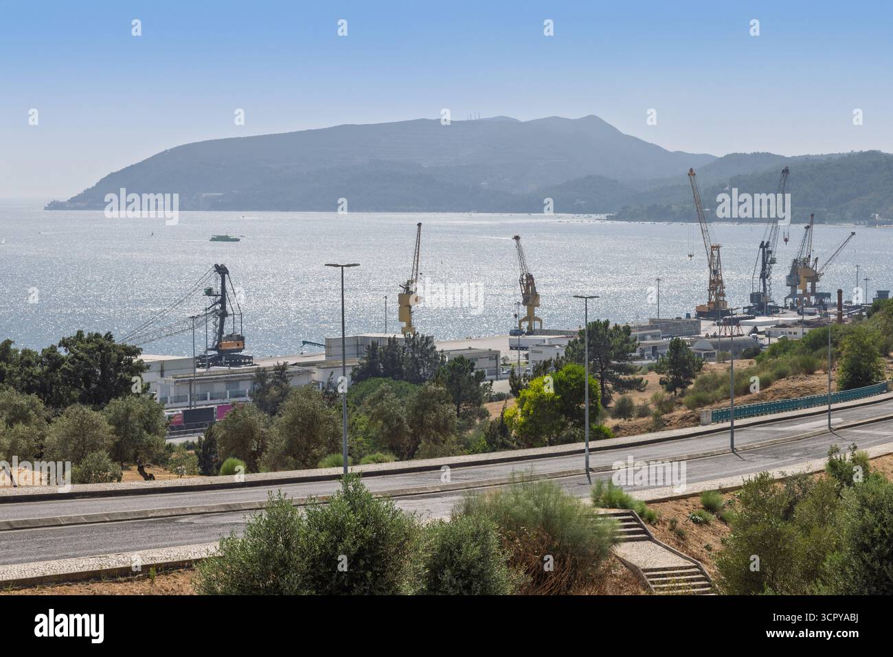 Le port de Setúbal est photographié par une journée ensoleillée avec une large étendue d'eau en arrière-plan et des montagnes à l'horizon. Plusieurs grues sont visibles Banque D'Images
