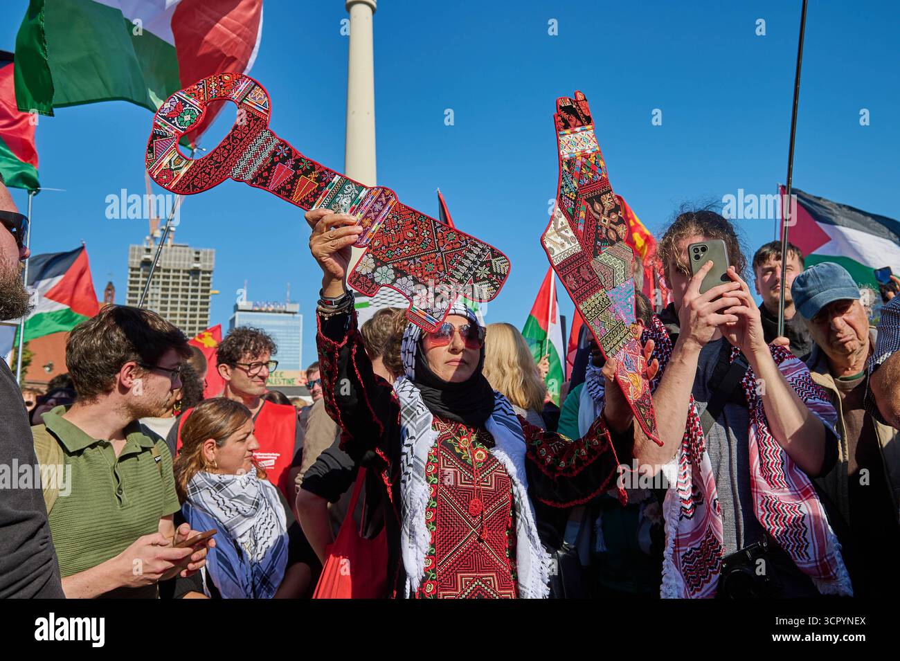 Grossdémonstration zusammen fuer Gaza am Samstag 27.09.2025 à Berlin. Foto : eine Demonstrantin haelt eine Landkarte von Palaestina und einen symbolischen Schluessel. Der Schluessel ist das Symbol fuer die in der Nakba verlorenen Haeuser, als im Zuge der Vertreibung und Flucht von 1948 mehr als die Haelfte der palaesinensischen Bevoelkerung des Mandatsgebiets Palaestina entweder vertrieben wurde oder vor der Gewalt floh und ihnen anschliessend das Recht auf Rueckkehr verweigert wurde. Der Schluessel Gilt als Teil des Willens und der Hoffnung auf Rueckkehr und als Anspruch auf den verlorenen BE Banque D'Images