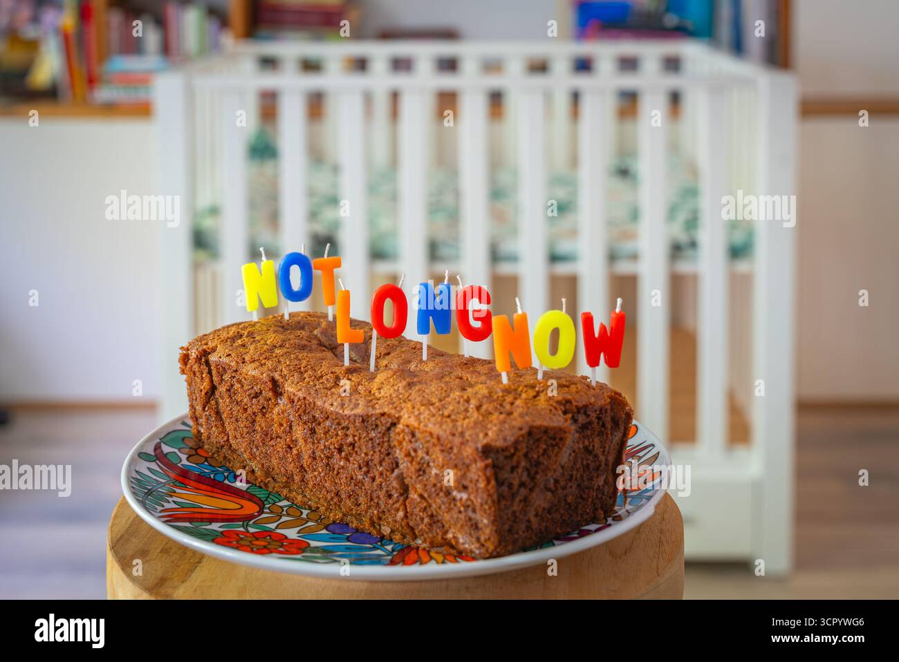 En attendant l’arrivée de bébé, gâteau avec le lettrage « Not long Now » devant la crèche, symbolisant l’anticipation de la parentalité Banque D'Images