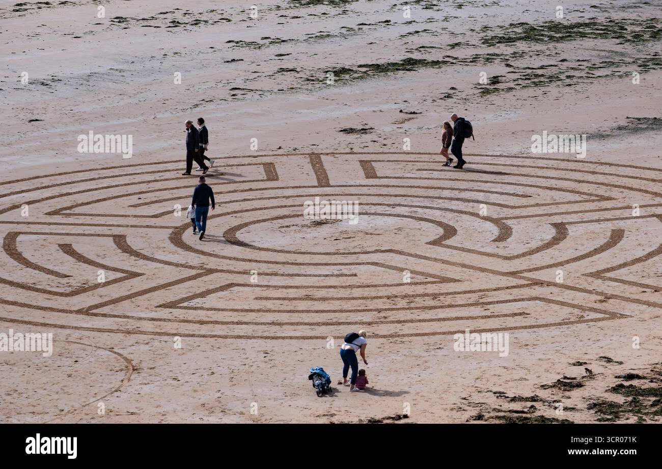Les vacanciers interagissent avec un labyrinthe géant art de sable sur la plage de Sandy Bay, Devon, Angleterre Banque D'Images