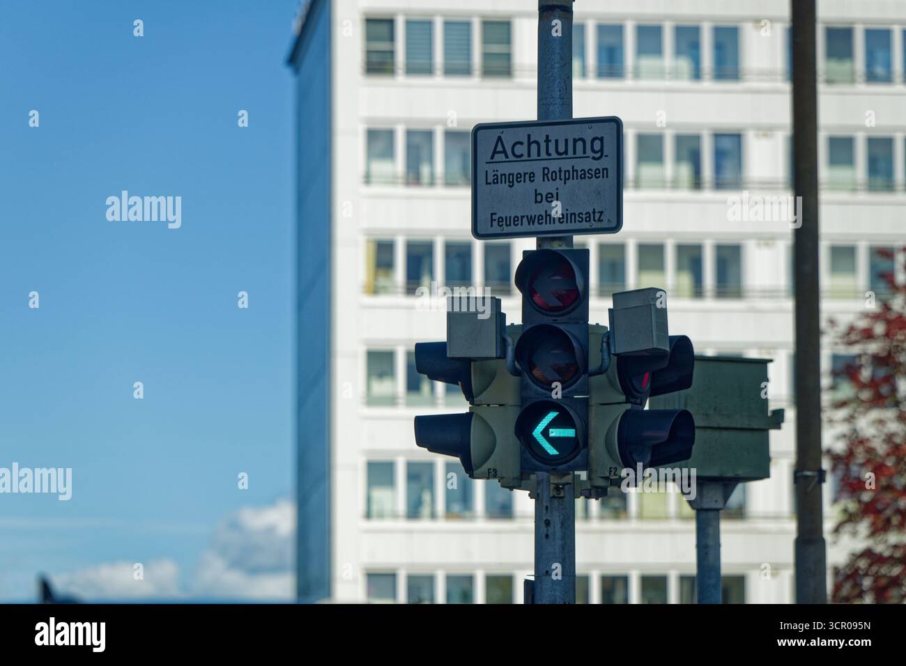 Le pôle montre le signal de flèche gauche qui s'allume en vert tandis que le texte d'avertissement laengere Rotphasen BEI feuerwehreinsatz signifie des phases de lumière rouge plus longues pendant Banque D'Images
