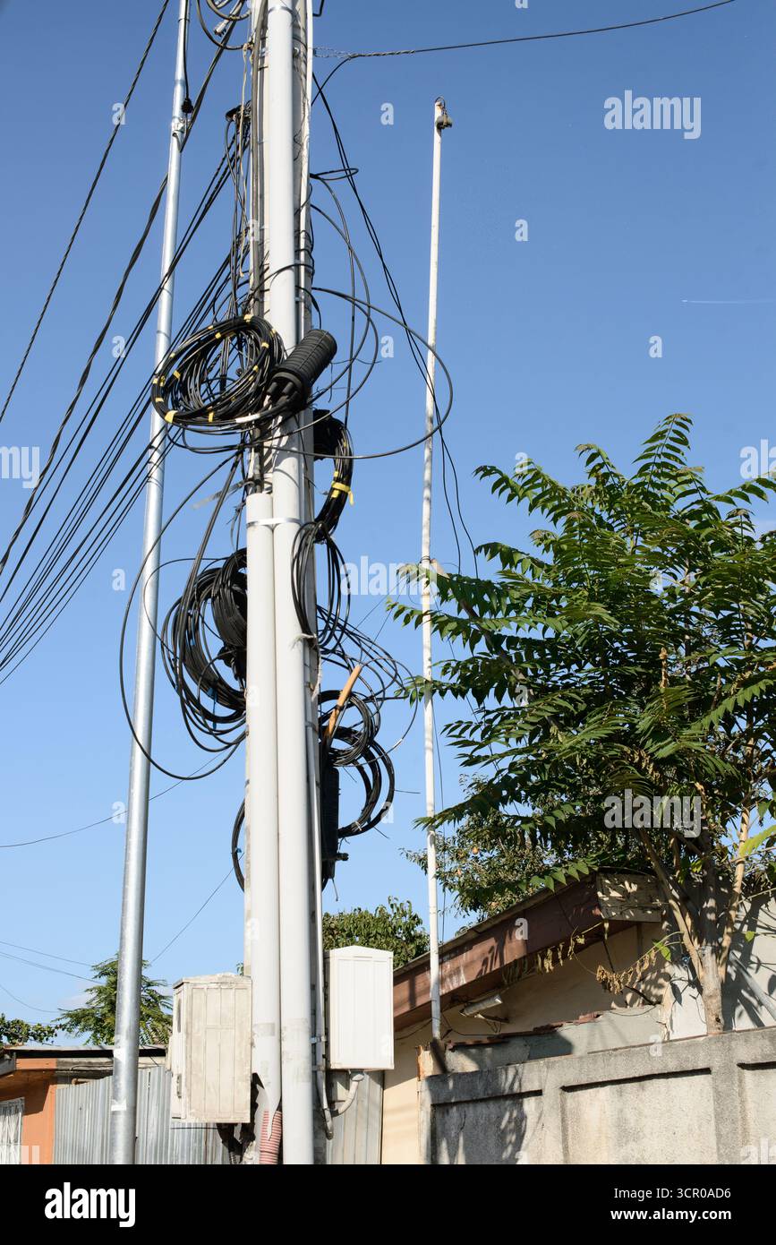 Poteau de service public urbain avec fibres enroulées et câbles électriques présentant un câblage de réseau dense pour les télécommunications et l'alimentation électrique dans un voisinage résidentiel Banque D'Images