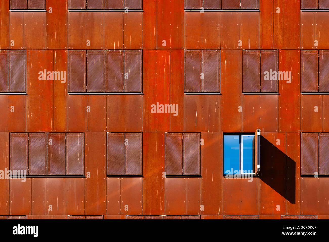 Façade architecturale moderne avec panneaux en métal rouillé et fenêtre ouverte unique créant un contraste visuel audacieux Banque D'Images