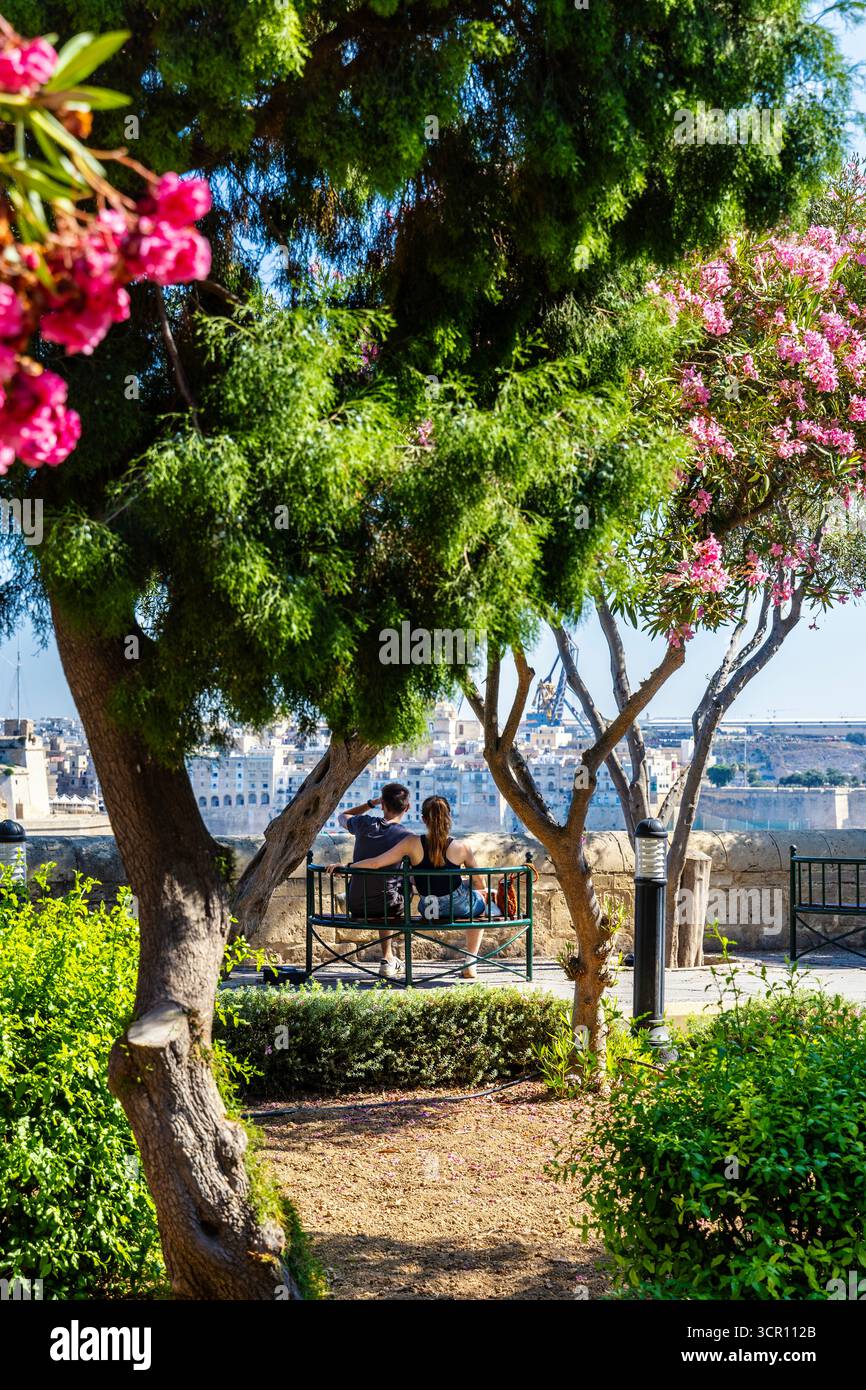 Couple assis sur un banc, lâchant à la vue dans les jardins de Lower Barrakka à la Valette, Malte Banque D'Images