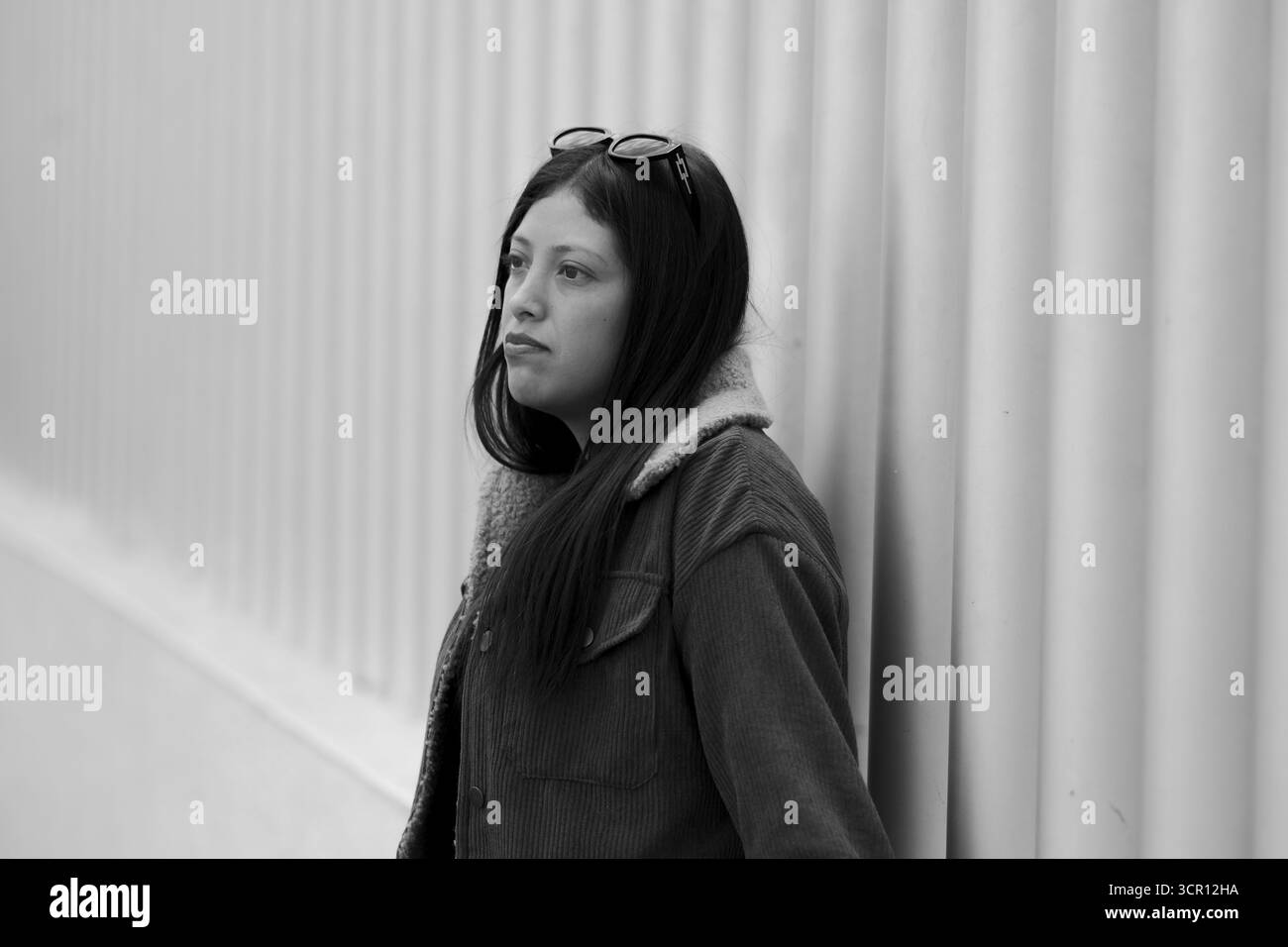 Portrait d'une jeune femme avec de longs cheveux droits et un haut blanc, debout dans un cadre de marché. Capturé avec lumière naturelle et faible profondeur de Banque D'Images