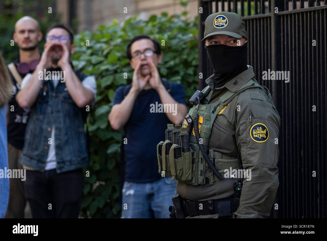 Pedestrians chant, "ICE go home!" as federal immigration agents stand on North Clark Street near West Oak Street in the River North neighborhood, Sunday, Sept. 28, 2025, in Chicago. (Ashlee Rezin/Chicago Sun-Times via AP) Banque D'Images