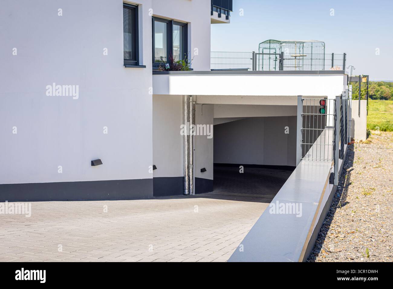 Cette scène met en valeur un immeuble résidentiel contemporain avec une grande entrée de garage accessible. La zone environnante est lumineuse, améliorant le Banque D'Images