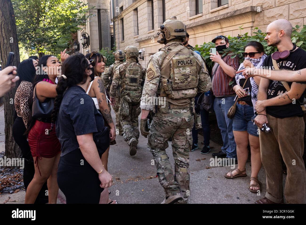 Pedestrians yell at federal agents from U.S. Immigration and Customs Enforcement and U.S. Customs and Border Protection as they walk along North Clark Street near West Oak Street in the River North neighborhood, Sunday, Sept. 28, 2025, in Chicago. (Ashlee Rezin/Chicago Sun-Times via AP) Banque D'Images