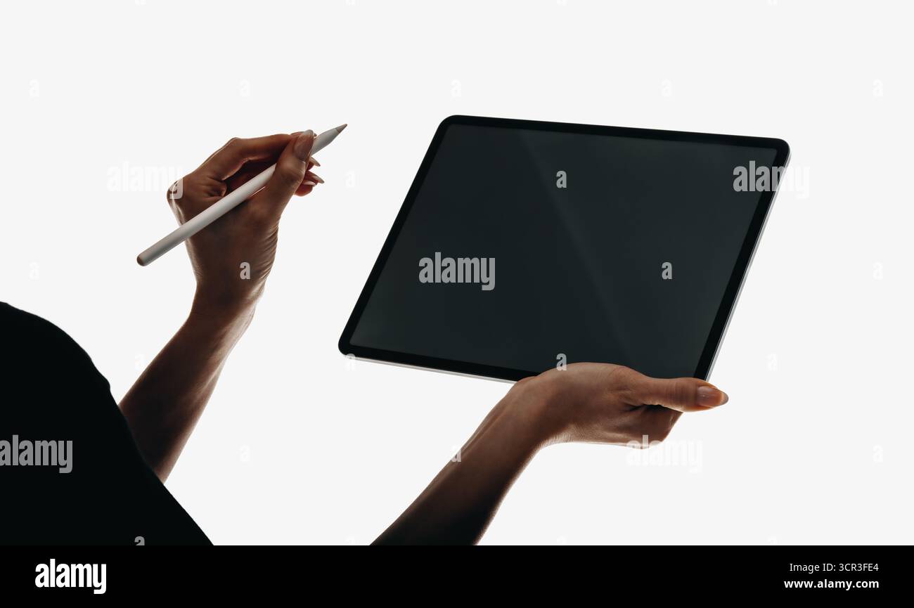 Vue rapprochée d'une personne utilisant un stylet avec une tablette numérique. La composition minimaliste montre le design élégant de l'appareil. Les mains illustrent i. Banque D'Images