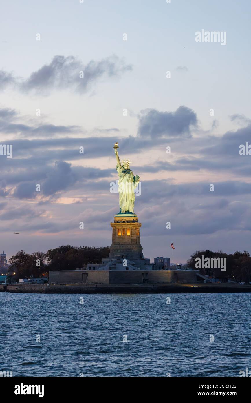 Statue de la liberté au coucher du soleil avec un ciel spectaculaire et une lumière dorée chaude se reflétant sur le monument Banque D'Images
