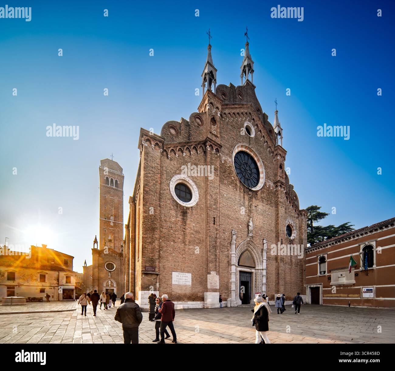 Les visiteurs se promènent près de Santa Maria Gloriosa dei Frari, admirant son architecture gothique et son atmosphère sereine au cœur de Venise. Banque D'Images