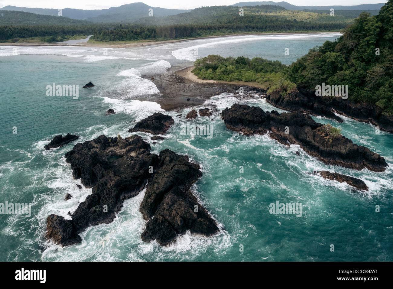 Paysage côtier pittoresque avec des rochers escarpés, une végétation luxuriante et des vagues turquoises s'écrasant à terre. Nias du Sud, Sumatra du Nord, Indonésie Banque D'Images Paysage côtier pittoresque avec des rochers escarpés, une végétation luxuriante et des vagues turquoises s'écrasant à terre. Nias du Sud, Sumatra du Nord, Indonésie Banque D'Images