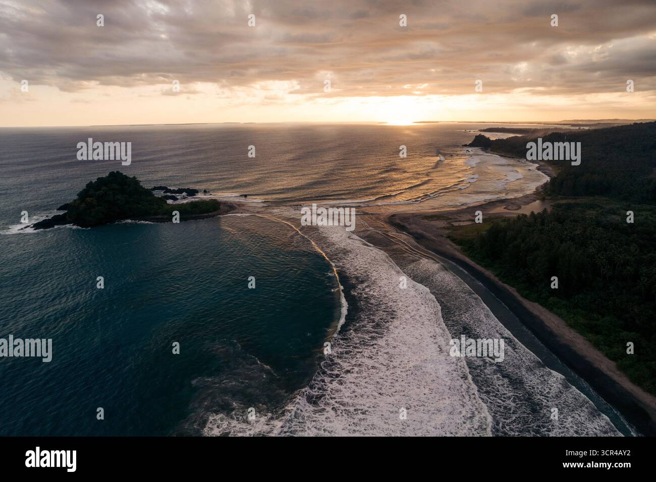 Superbe vue aérienne d'un coucher de soleil serein sur l'océan avec une côte luxuriante et des vagues douces. Nias du Sud, Sumatra du Nord, Indonésie Banque D'Images Superbe vue aérienne d'un coucher de soleil serein sur l'océan avec une côte luxuriante et des vagues douces. Nias du Sud, Sumatra du Nord, Indonésie Banque D'Images