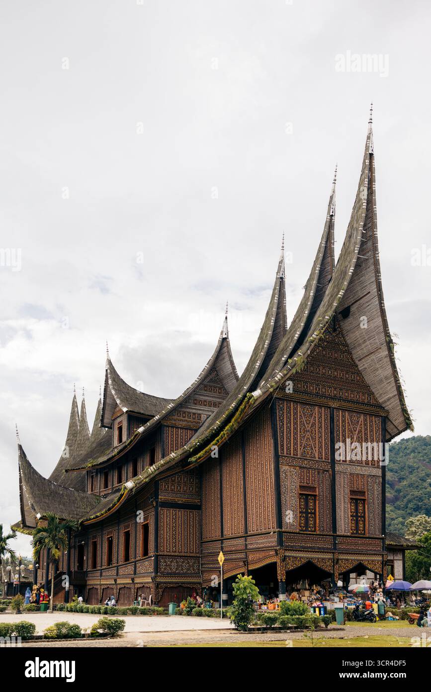 Maison traditionnelle indonésienne Minangkabau avec toit incurvé spectaculaire sous ciel nuageux. Batusangkar, Sumatra Ouest, Indonésie Banque D'Images