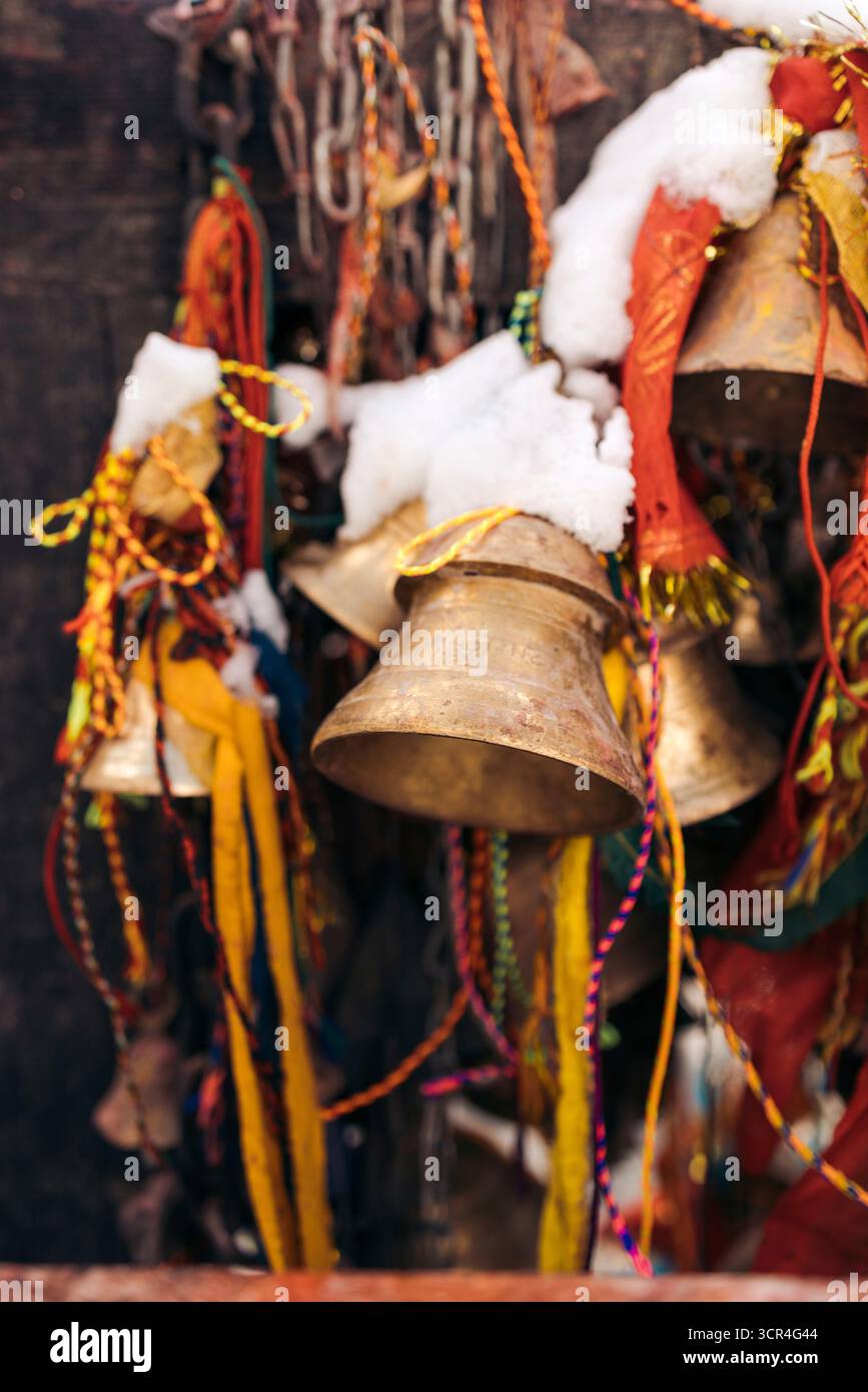 Cloches recouvertes de neige, ornées de rubans colorés et de tissus dans un cadre extérieur. Muktinath, Annapurna, district de Mustang, province de Gandaki, Népal Banque D'Images