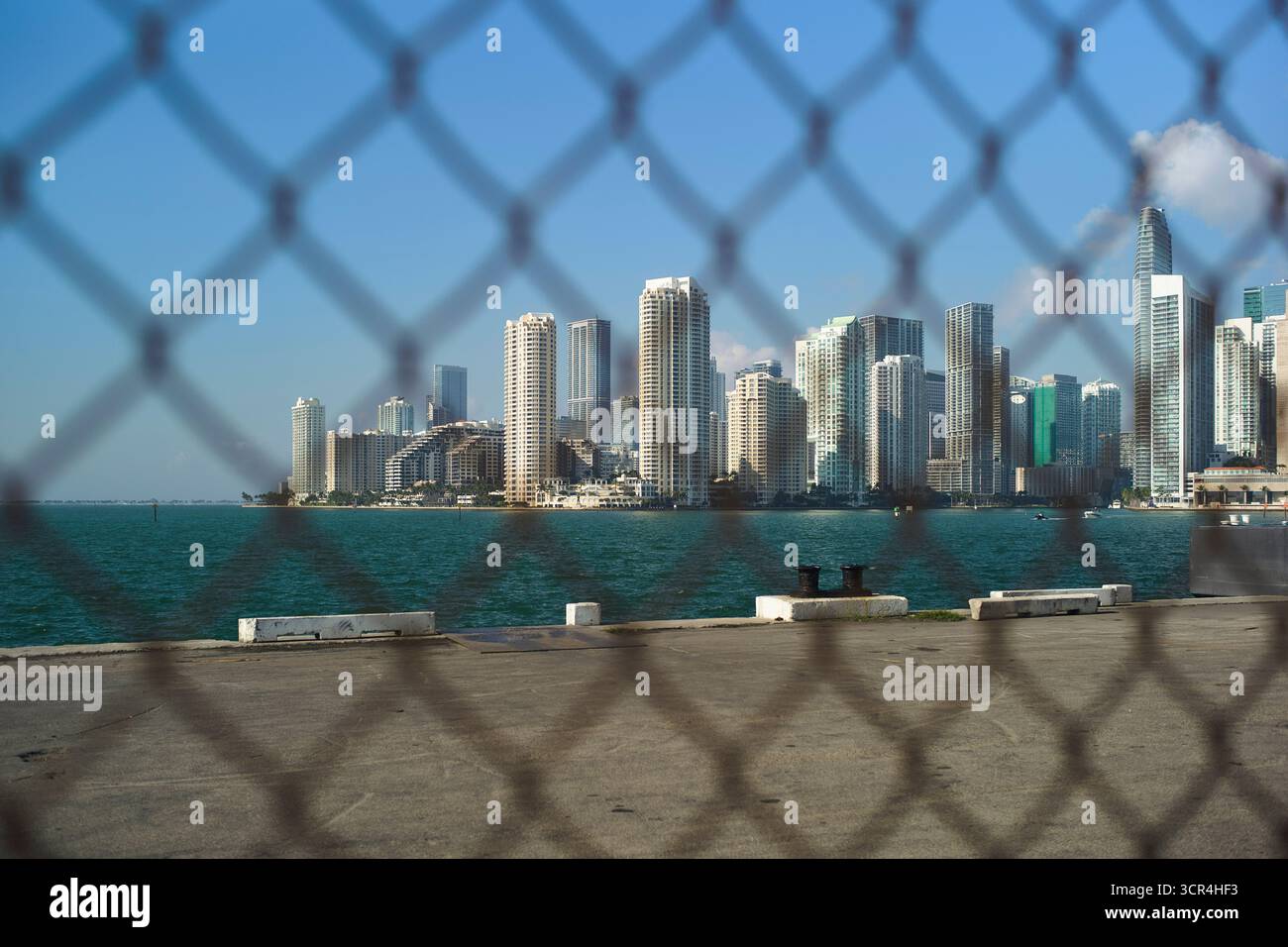 Gratte-ciel près du front de mer vu à travers une clôture à maillons de chaîne par une journée ensoleillée. Miami, Floride, États-Unis Banque D'Images