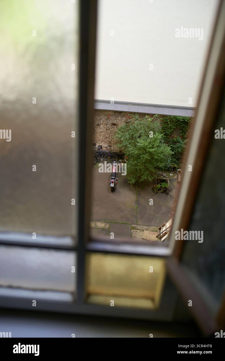 Vue par la fenêtre sur une cour avec un arbre et un vélo garé. Berlin, Allemagne Banque D'Images Vue par la fenêtre sur une cour avec un arbre et un vélo garé. Berlin, Allemagne Banque D'Images
