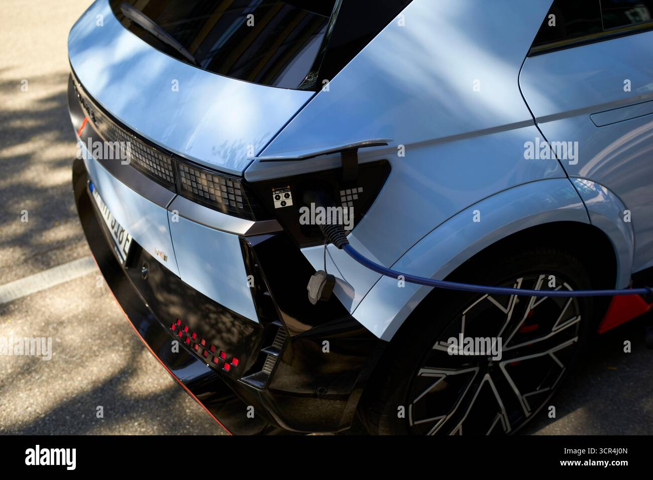 Voiture électrique élégante se chargeant en plein soleil sur la rue pavée. Stuttgart, Allemagne Banque D'Images