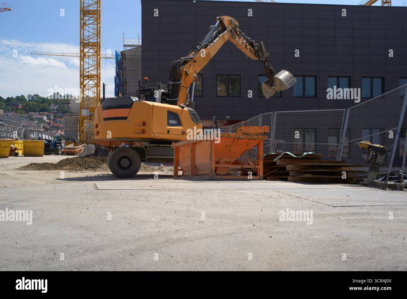 Excavatrice déplaçant le sol sur un chantier de construction près d'un bâtiment moderne. Stuttgart, Allemagne Banque D'Images