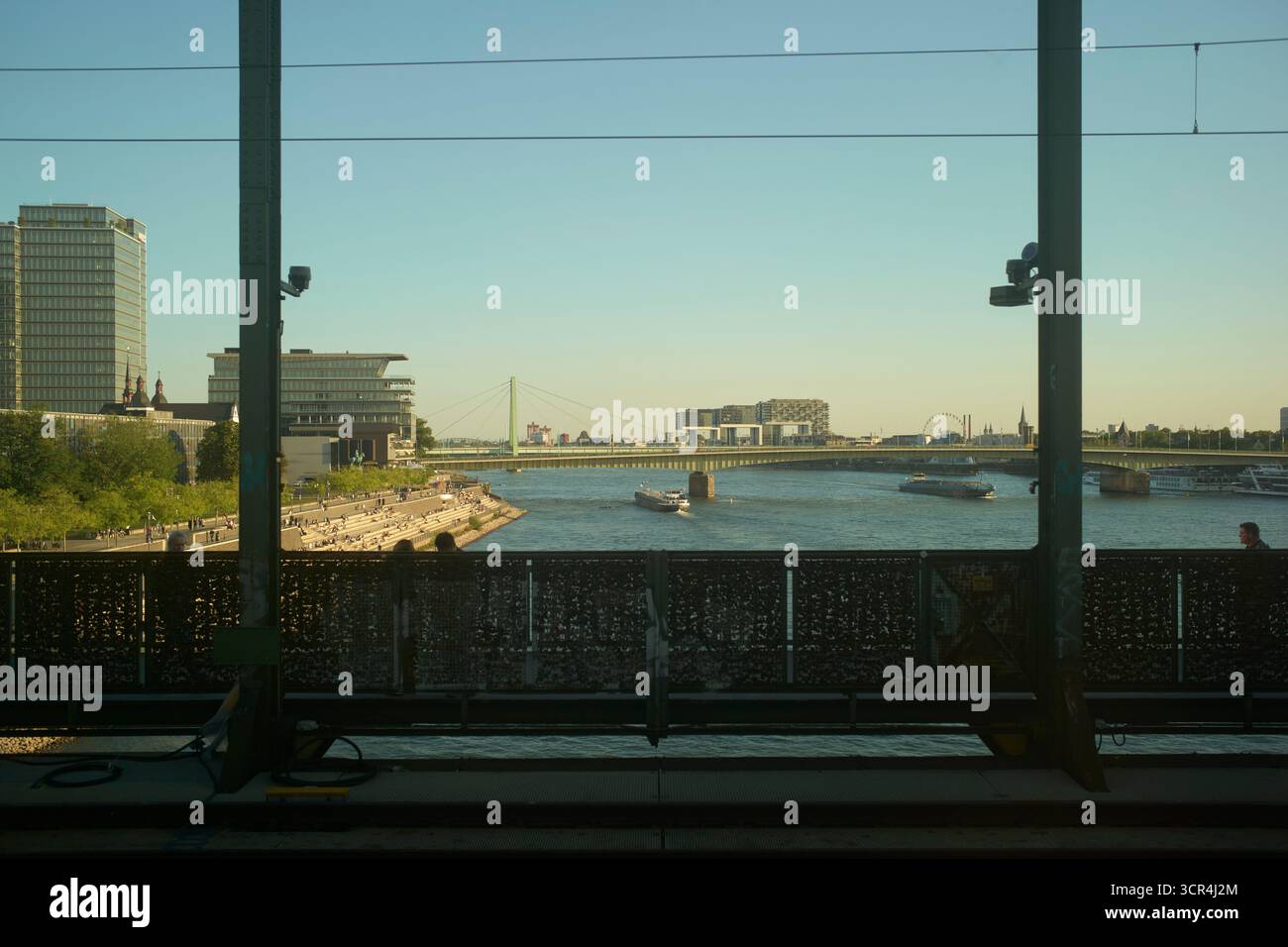 Vue sur la rivière urbaine avec pont, bâtiments modernes et eau calme sous un ciel dégagé. Cologne, Allemagne Banque D'Images